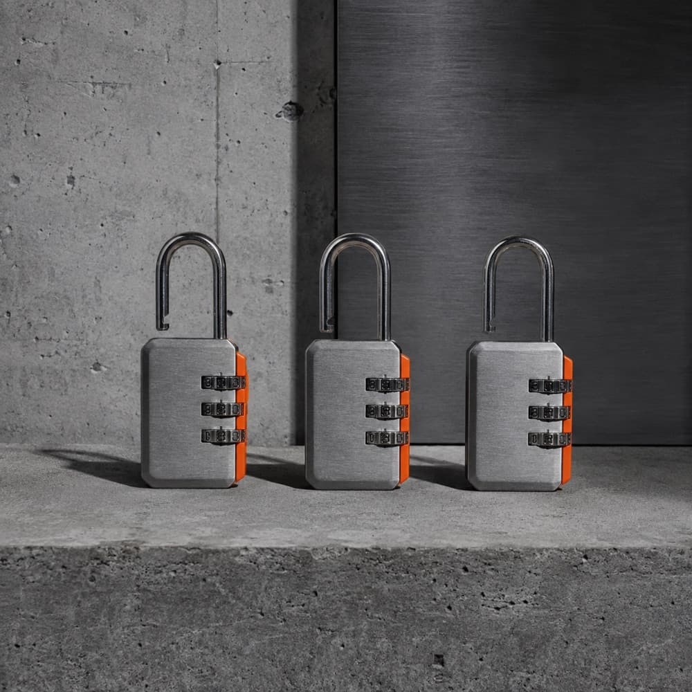 Three identical combination padlocks in a row on concrete, shackles open.